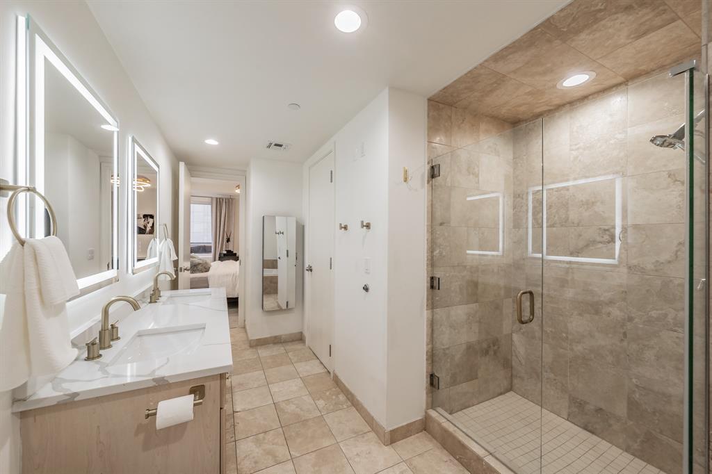1505 Elm Street, Unit 404 Dallas, TX 75201 - Photo 22 of 40 a bathroom with a granite countertop sink mirror and shower