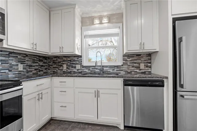a kitchen with white cabinets and sink