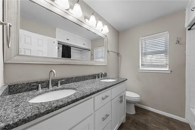 a bathroom with a granite countertop sink a toilet and mirror