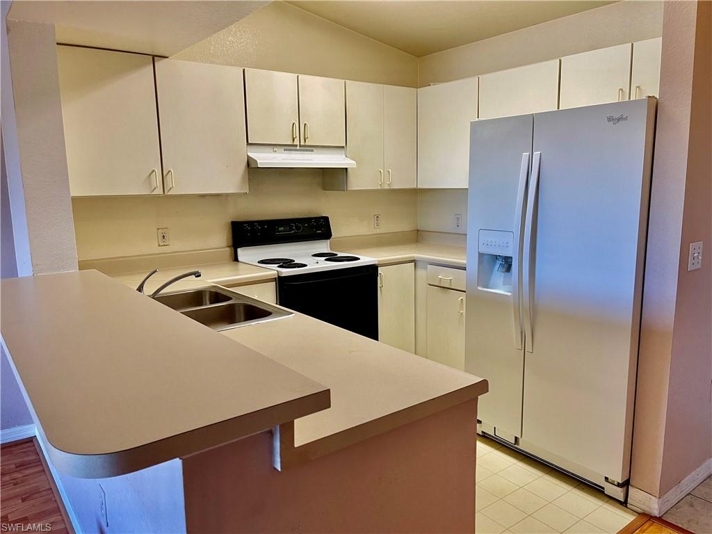 8274 Key Royal Circle, Unit 1032 Naples, FL 34119 - Photo 4 of 16 a kitchen with stainless steel appliances a refrigerator a stove a sink and white cabinets