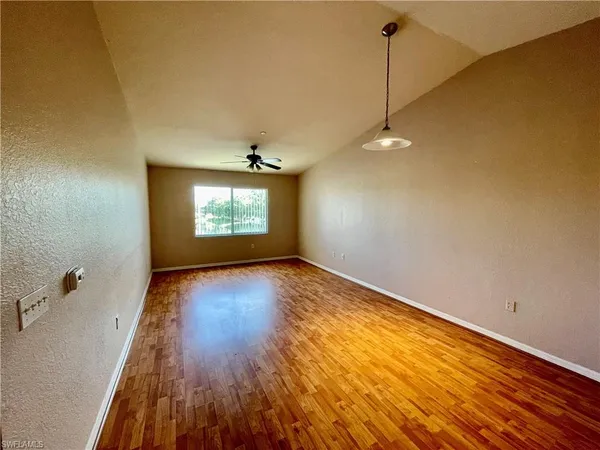 a view of empty room with wooden floor and fan
