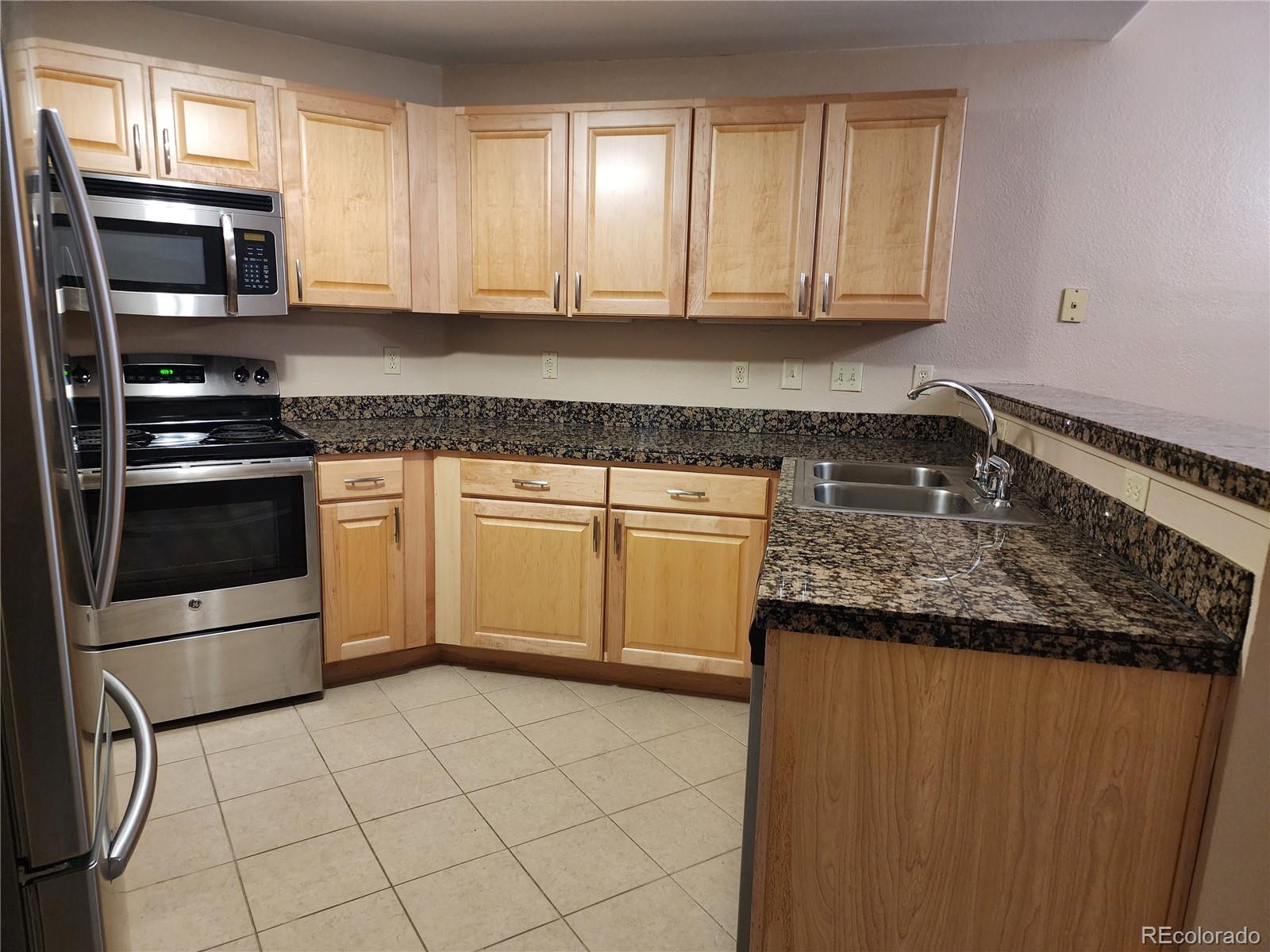 8601 East Dry Creek Road, Unit 112 Centennial, CO 80112 - Photo 9 of 19 a kitchen with granite countertop a stove sink and microwave
