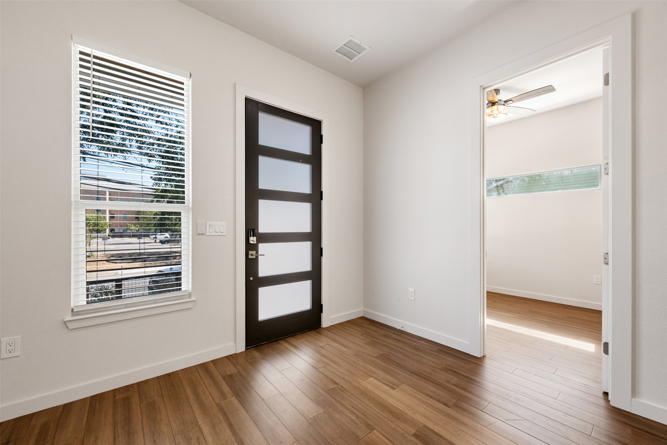 3010 Webberville Road, Unit 1 Austin, TX 78702 - Photo 13 of 38 Modern entry door with five frosted glass panels, wood-finish flooring, and a large window with blinds
