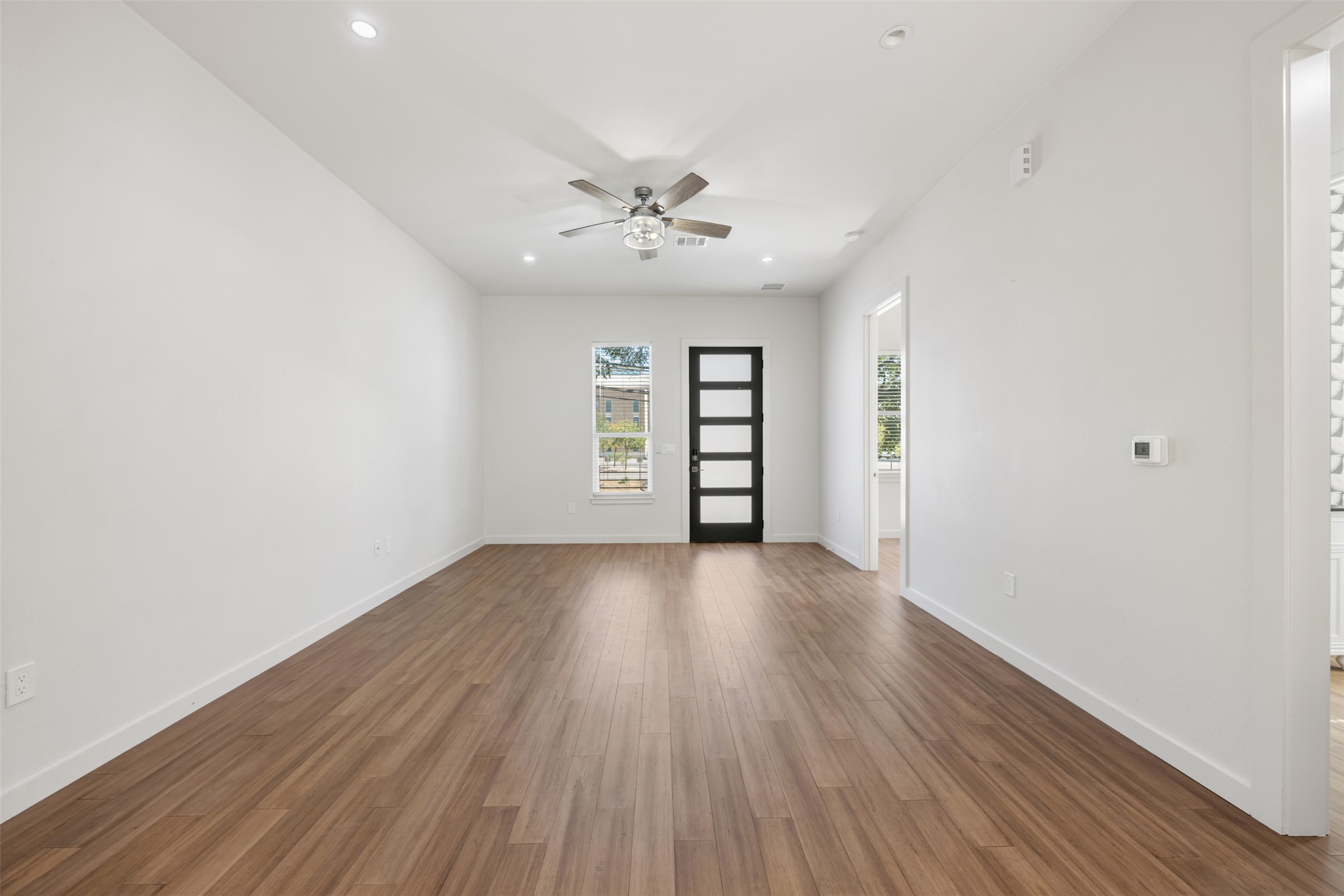 3010 Webberville Road, Unit 1 Austin, TX 78702 - Photo 19 of 38 an empty room with wooden floor chandelier fan and windows