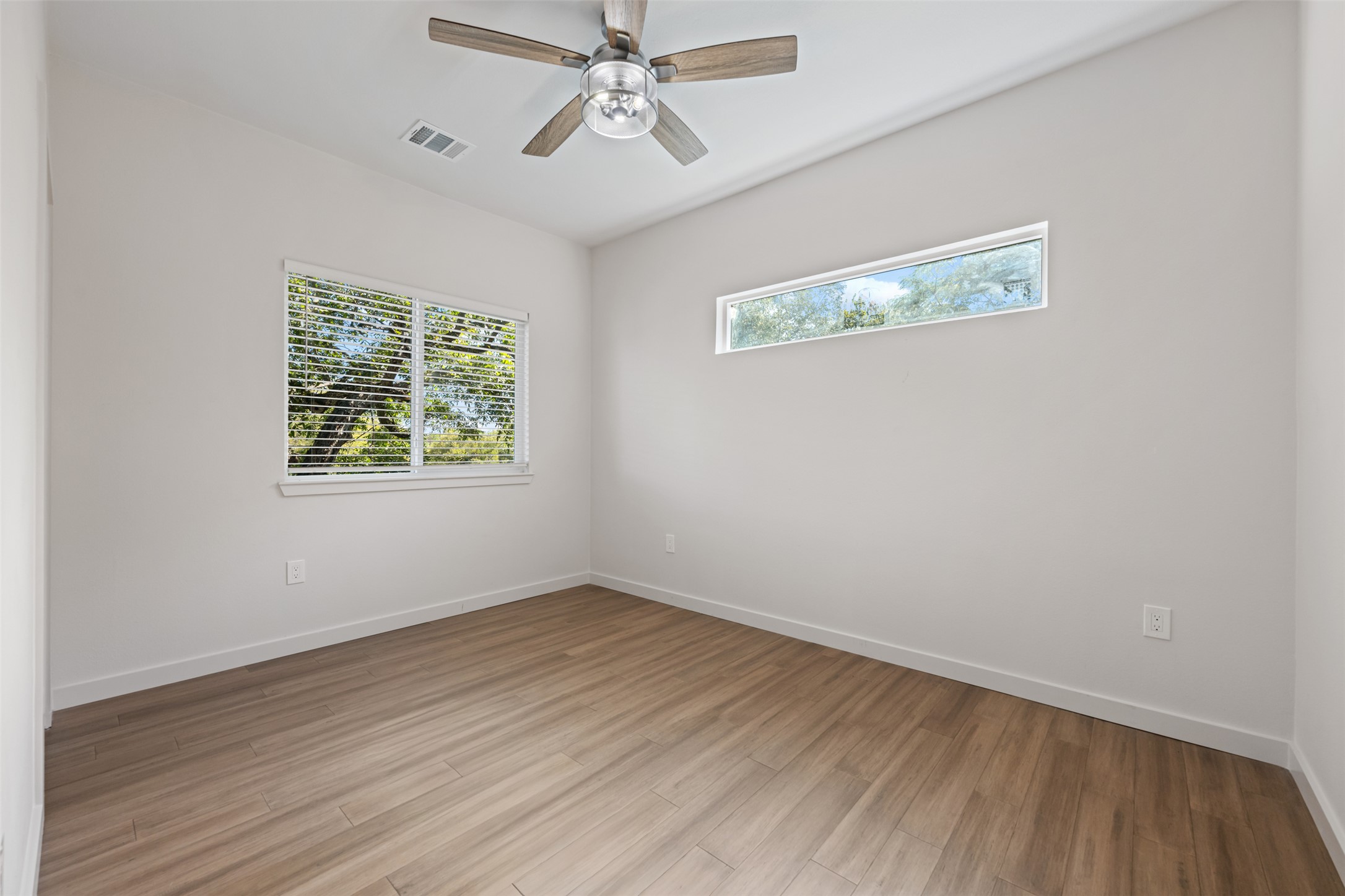 3010 Webberville Road, Unit 1 Austin, TX 78702 - Photo 37 of 38 Light-filled interior featuring wood-finish flooring, a modern ceiling fan, and white walls