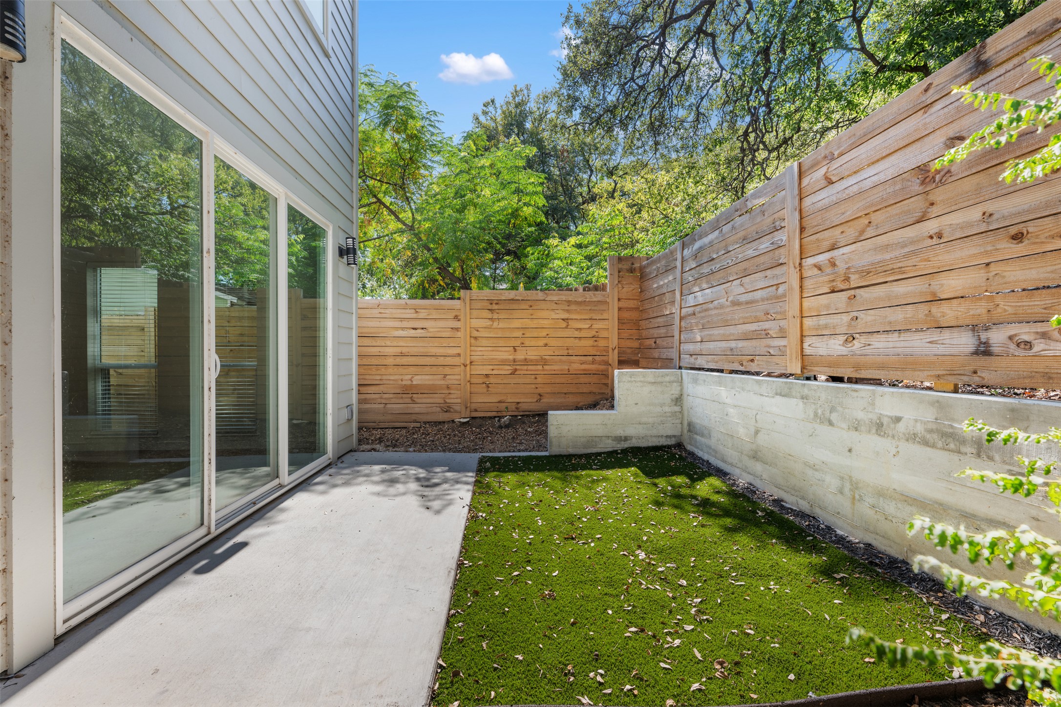 3010 Webberville Road, Unit 1 Austin, TX 78702 - Photo 9 of 38 Private outdoor patio featuring a concrete slab, artificial turf, and a wood privacy fence