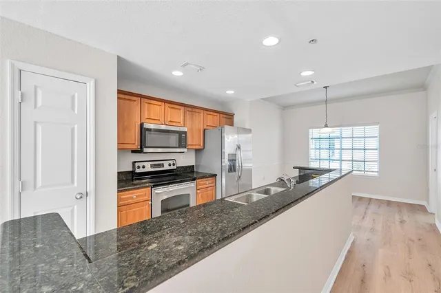 a kitchen with stainless steel appliances granite countertop a sink stove and refrigerator