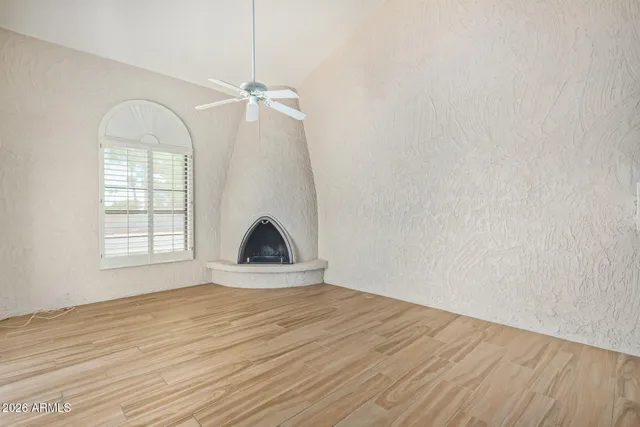 a view of empty room with wooden floor and fan