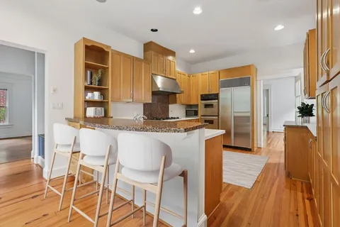 a kitchen with granite countertop kitchen island stainless steel appliances a sink and a refrigerator