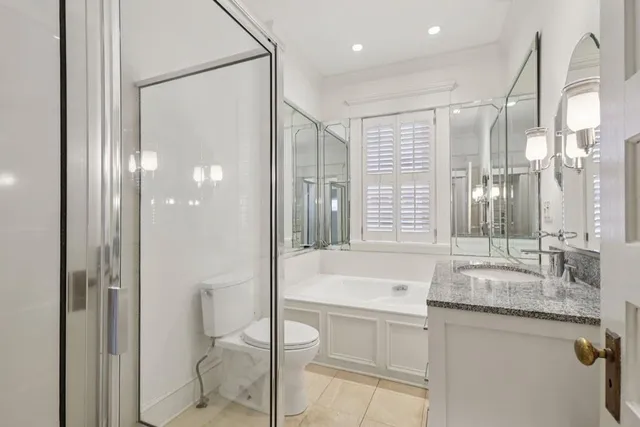 a bathroom with a granite countertop sink a toilet and shower