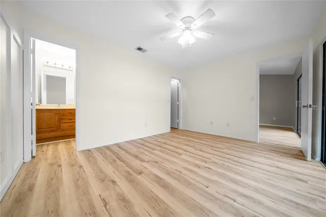 a view of empty room with wooden floor and fan