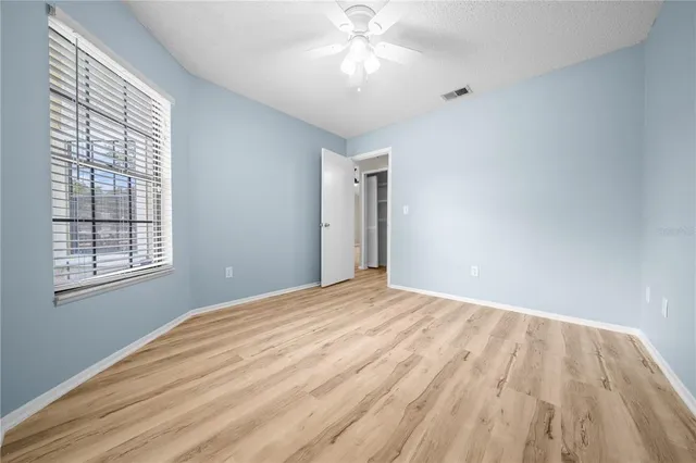 a view of empty room with window and ceiling fan