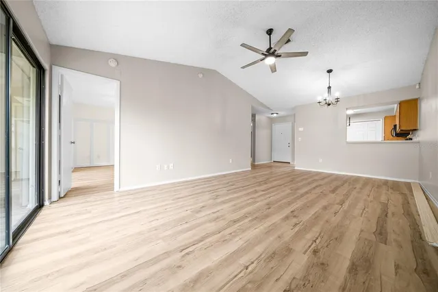 a view of empty room with wooden floor and ceiling fan