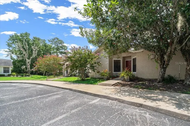 a view of a house with a yard and large trees