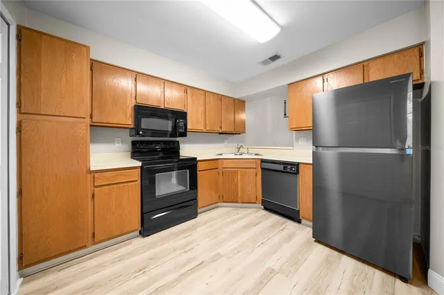 a kitchen with a refrigerator stainless steel appliances wooden floor and cabinet