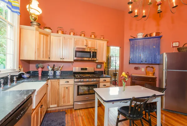 a kitchen with stainless steel appliances a stove top oven a sink a dining table and chairs