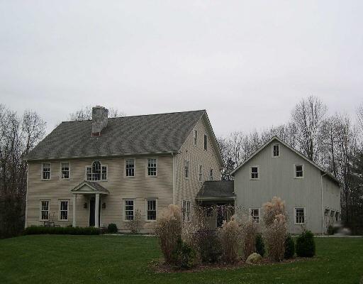 a view of a white house next to a yard with big trees