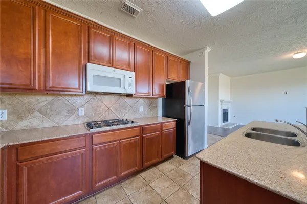 a kitchen with stainless steel appliances granite countertop wooden cabinets a refrigerator and a sink