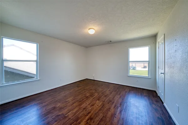 an empty room with wooden floor and windows