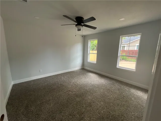 an empty room with windows and ceiling fan