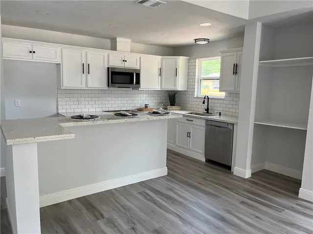 a kitchen with stainless steel appliances granite countertop a sink a stove a refrigerator and cabinets