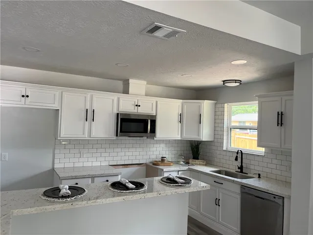 a kitchen with sink a stove and cabinets