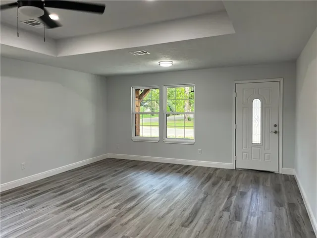 an empty room with wooden floor and windows
