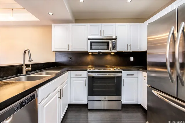 a kitchen with granite countertop white cabinets white stainless steel appliances and a sink