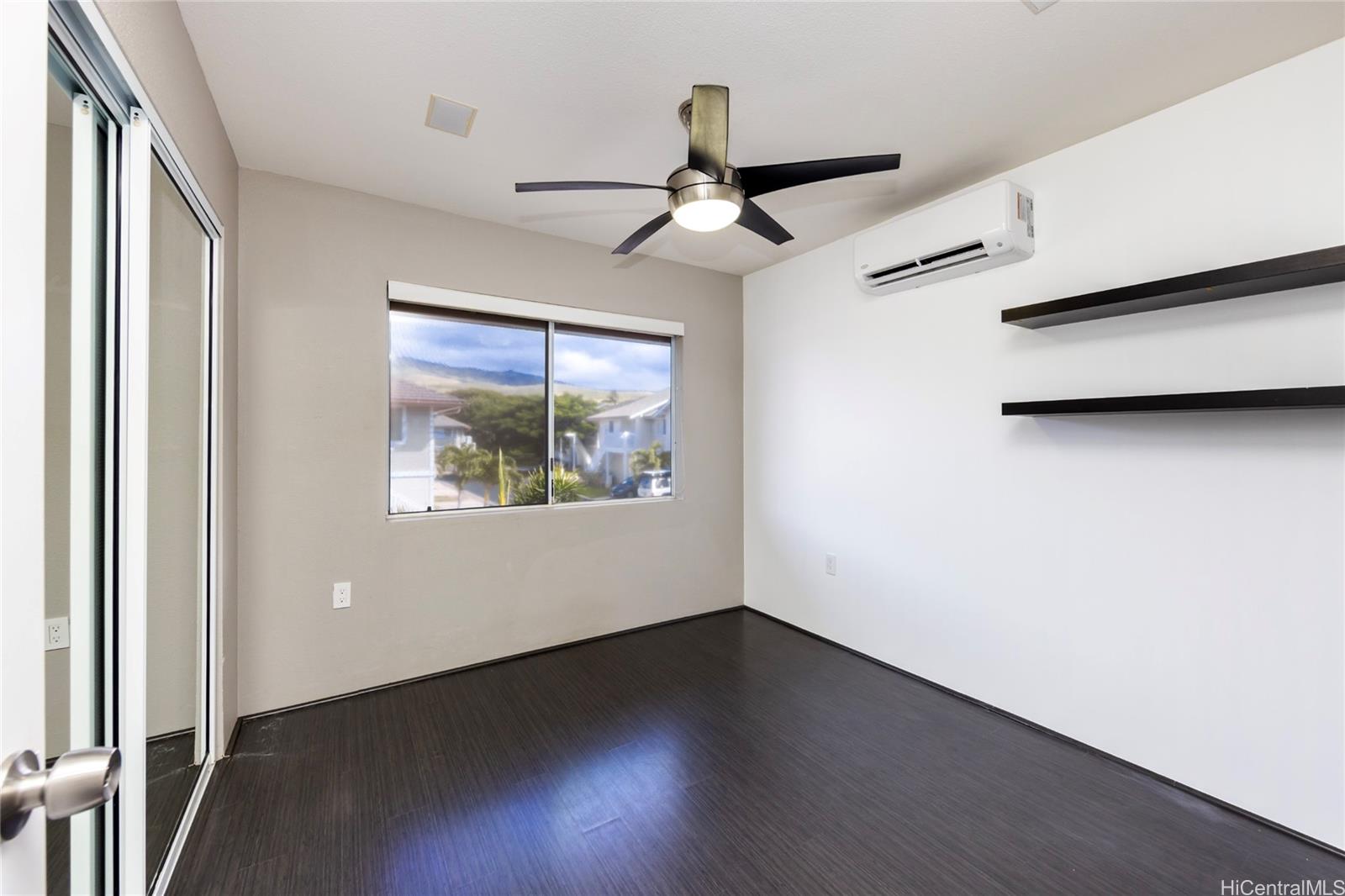 92-1475 Ali'inui Drive, Unit 20B Kapolei, HI 96707 - Photo 8 of 18 an empty room with wooden floor chandelier fan and windows