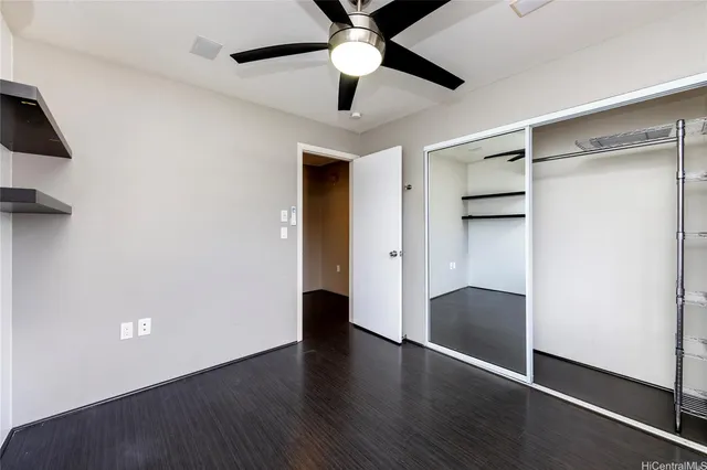 an empty room with wooden floor and a ceiling fan