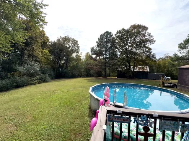 a view of swimming pool with seating area and trees in the background
