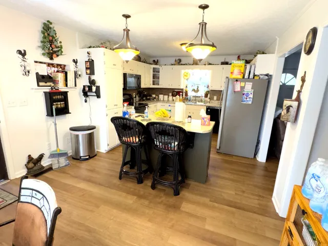 a room with stainless steel appliances kitchen island granite countertop a table chairs and a refrigerator