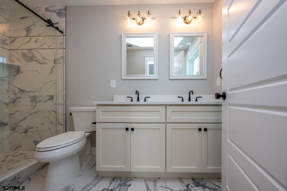 4 Wesley Road Ocean City, NJ 08226 - Photo 25 of 44 a bathroom with a granite countertop toilet a sink a mirror and a shower