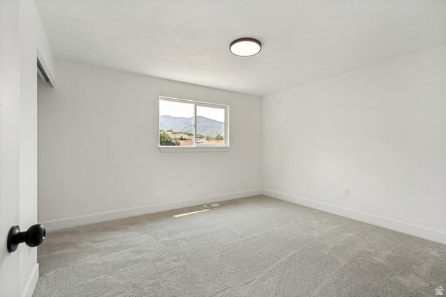 62 South Clark Lane Elk Ridge, UT 84651 - Photo 12 of 30 Spacious primary bedroom featuring light gray carpet flooring, a window offering a mountain landscape, a modern flush-mount ceiling light fixture, and white painted walls