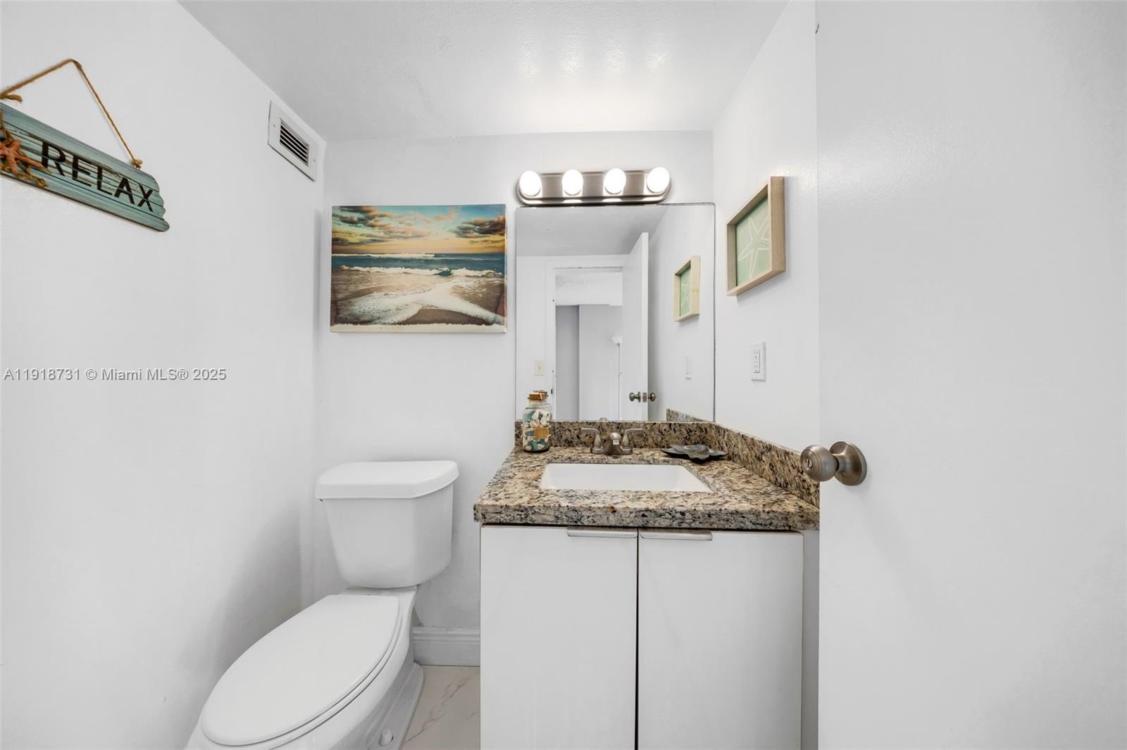 17011 North Bay Road, Unit 718 Sunny Isles Beach, FL 33160 - Photo 19 of 24 a bathroom with a granite countertop sink and a mirror with toilet