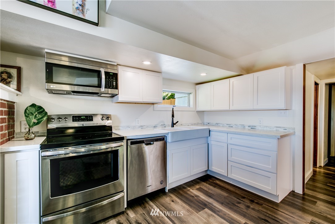 4401 Sunset Beach Road West University Place, WA 98466 - Photo 20 of 40 a kitchen with stainless steel appliances white cabinets and a stove top oven