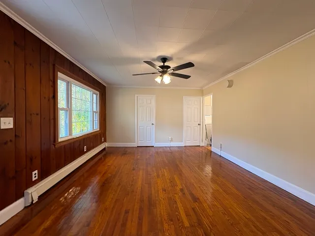 a view of an empty room with a window and wooden floor