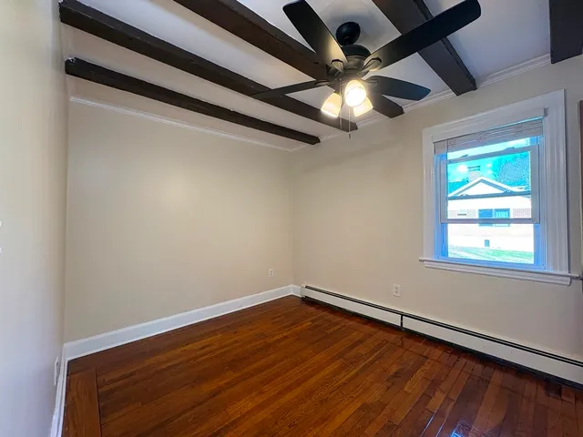 an empty room with wooden floor fan and windows