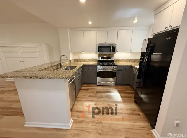 a kitchen with stainless steel appliances granite countertop a sink stove microwave and refrigerator