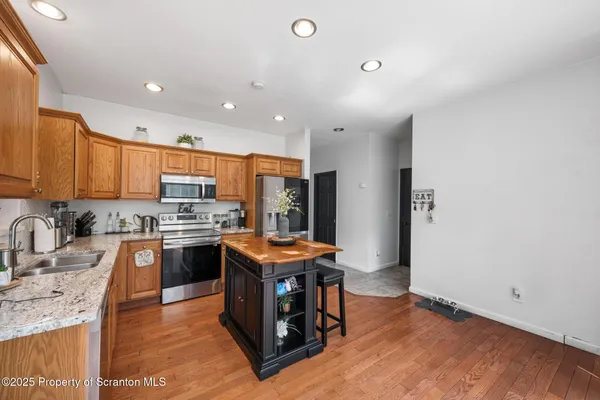 a kitchen with stainless steel appliances granite countertop a sink stove refrigerator and wooden cabinets