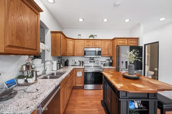 a kitchen with stainless steel appliances granite countertop wooden cabinets a stove top oven a granite counter space and a sink