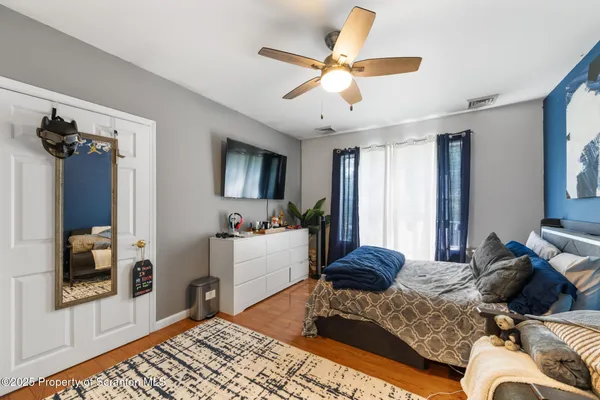a bedroom with a bed couches and a flat tv screen