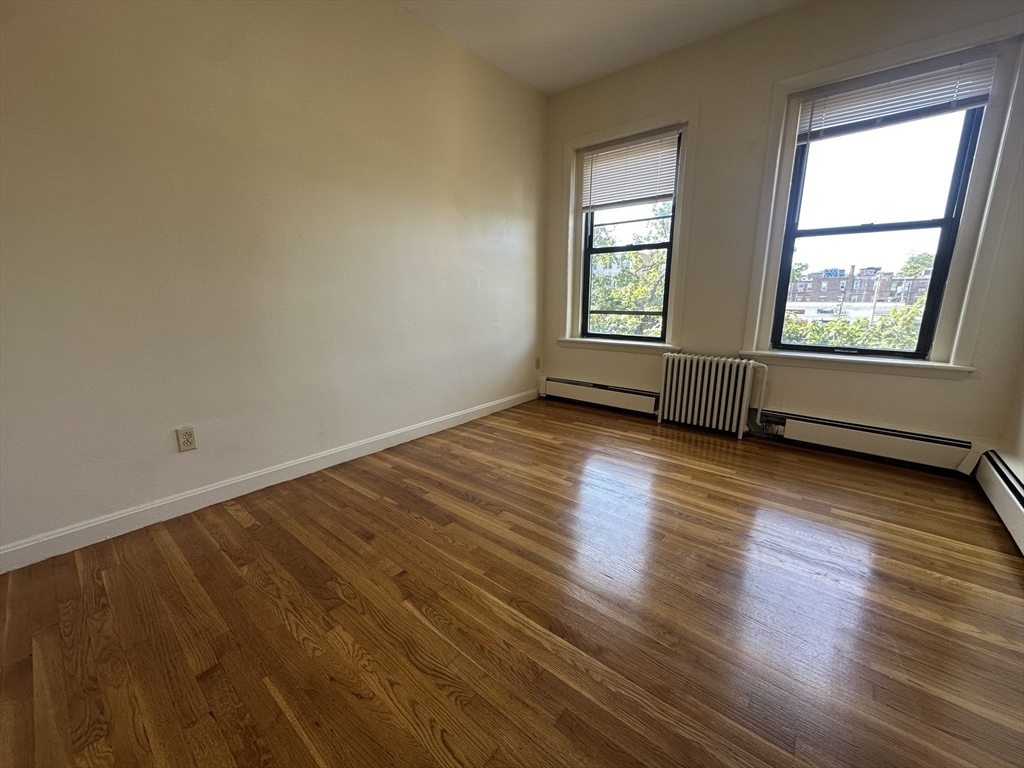 1238 Commonwealth Avenue, Unit 51 Boston, MA 02134 - Photo 6 of 10 an empty room with wooden floor and windows
