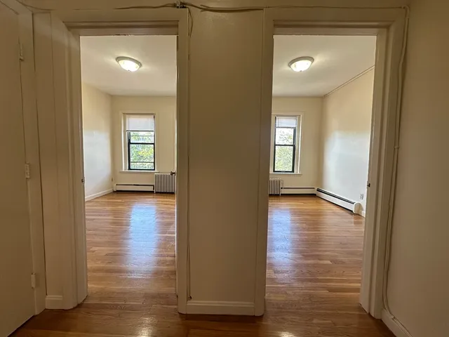 a view of empty room with wooden floor and fan