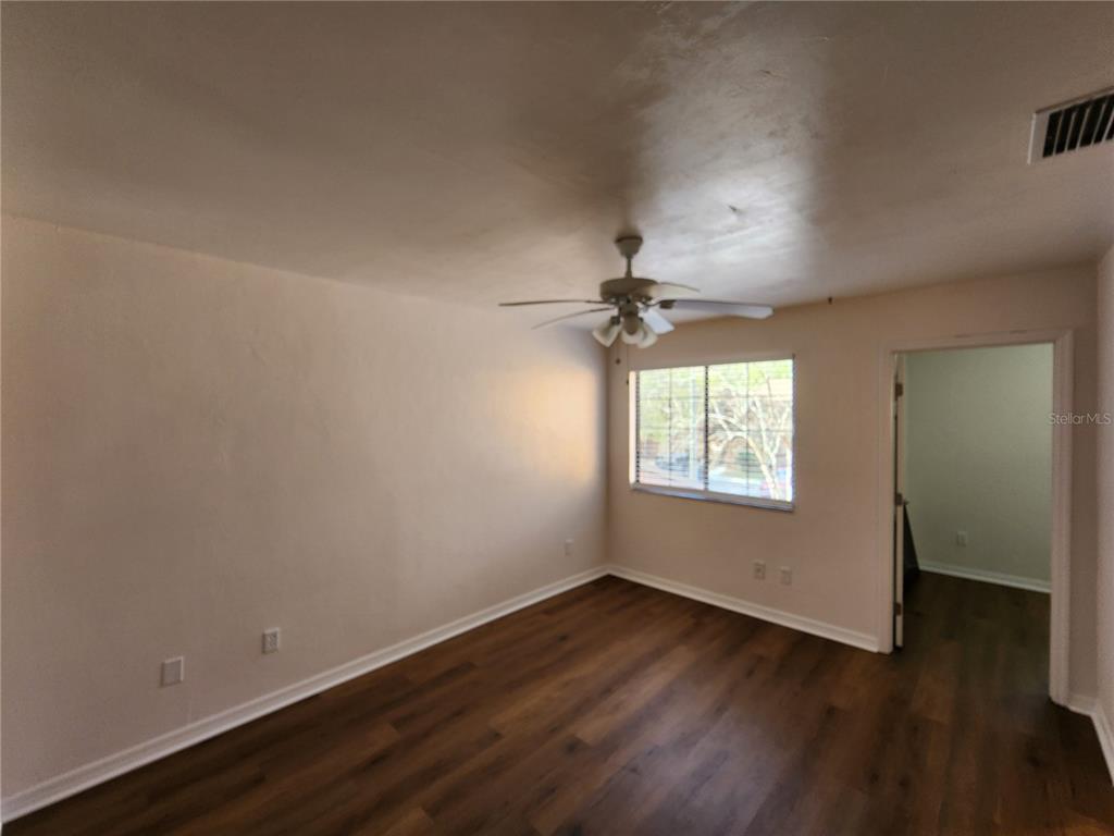 5823 Southwest 9th Place, Unit H55 Gainesville, FL 32607 - Photo 38 of 50 an empty room with wooden floor chandelier fan and windows