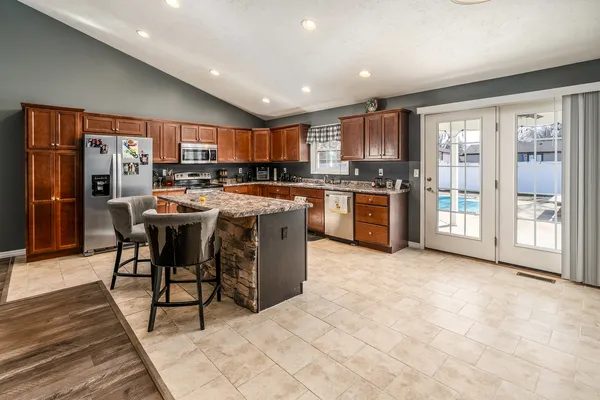 a open kitchen with stainless steel appliances granite countertop a stove top oven a sink dishwasher and a refrigerator with wooden cabinets