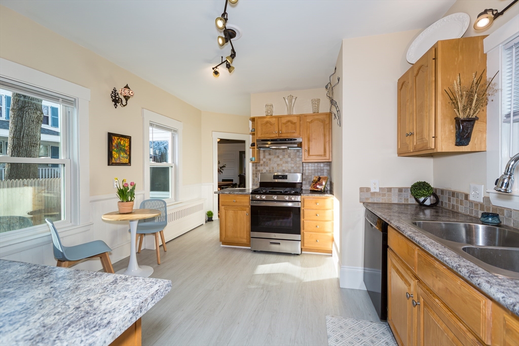62 Central Street Framingham, MA 01701 - Photo 12 of 35 a kitchen with stainless steel appliances granite countertop a stove top oven a sink a dining table and chairs with wooden floor