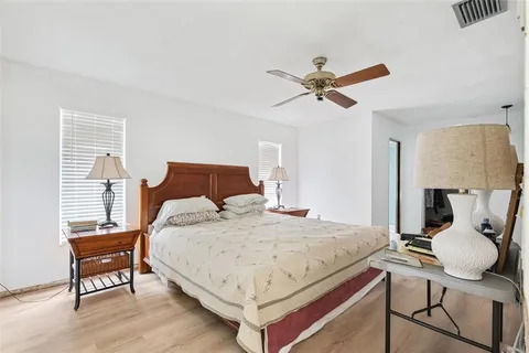 a bedroom with a bed and dresser with wooden floor