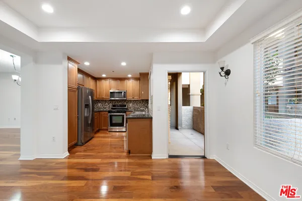 a view of a kitchen with kitchen island wooden floor center island and stainless steel appliances