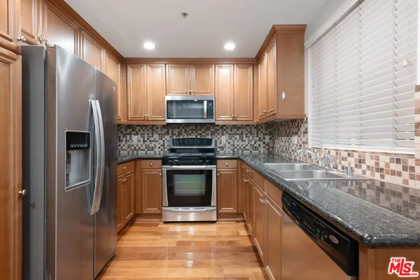 a kitchen with stainless steel appliances granite countertop a sink stove and refrigerator
